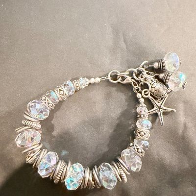 chunky silver-toned charm bracelet featuring large faceted crystal beads and playful ocean-themed dangles like a starfish and a sea turtle.
