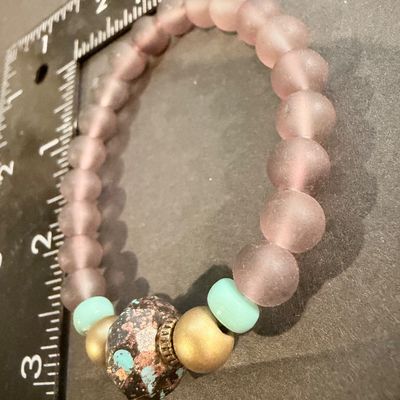 handmade beaded stretch bracelet featuring frosted mauve beads and a distinctive patterned focal stone.