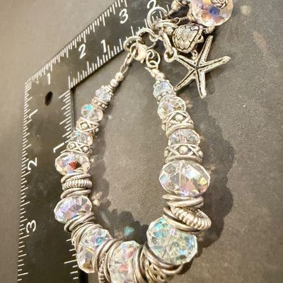 chunky silver-toned charm bracelet featuring large faceted crystal beads and playful ocean-themed dangles like a starfish and a sea turtle.