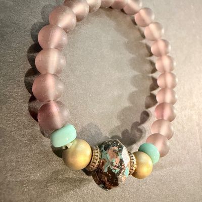 handmade beaded stretch bracelet featuring frosted mauve beads and a distinctive patterned focal stone.