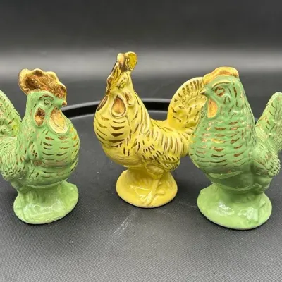 mid-20th century set of three ceramic rooster and hen figurines with gold trim.