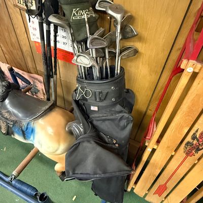 Vintage golf bag filled with an assortment of irons and woods, including a King Cobra driver with a green headcover.