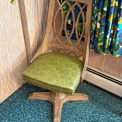Mid-century modern swivel desk chair featuring an openwork wooden backrest and a green patterned vinyl seat cushion.