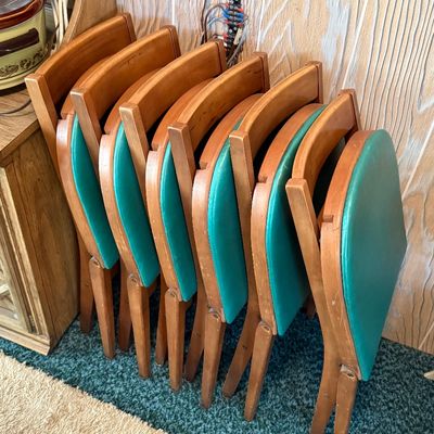 Set of six mid-century folding chairs featuring wooden frames and teal vinyl padded seats.