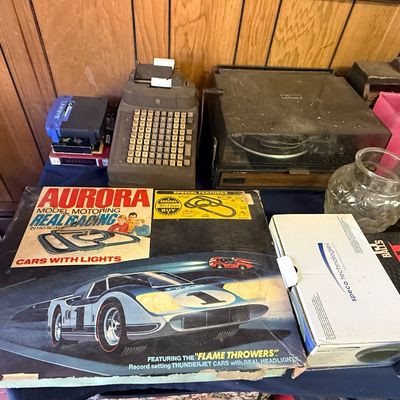 Vintage Aurora Model Motoring Real Racing slot car set in its original box, displayed alongside a vintage adding machine, a turntable,...