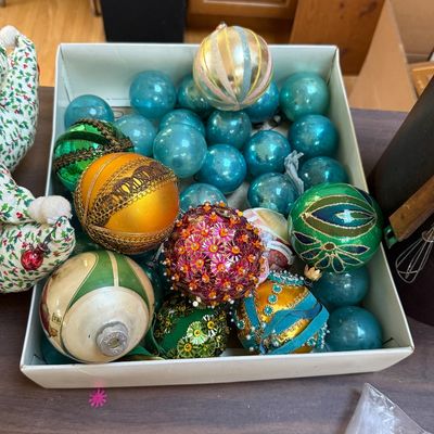 Collection of vintage Christmas ornaments, featuring a mix of solid blue glass balls and ornate, hand-decorated sequined and beaded baubles.