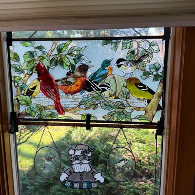 Stained glass window panel depicting a variety of colorful songbirds perched on leafy branches, accompanied by three smaller hanging...
