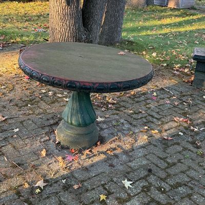Vintage concrete garden table featuring a round top with a decorative egg-and-dart border, supported by a fluted pedestal base with...