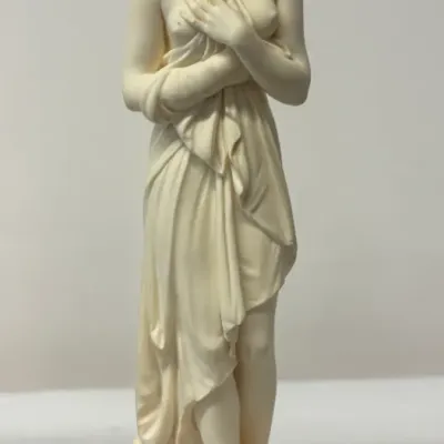 Classical-style alabaster or resin figurine of a draped female figure, mounted on a round, polished marble base. Singed