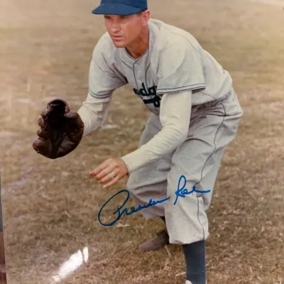 Autographed color photograph of Brooklyn Dodgers pitcher Preacher Roe in a fielding pose, signed in blue ink.