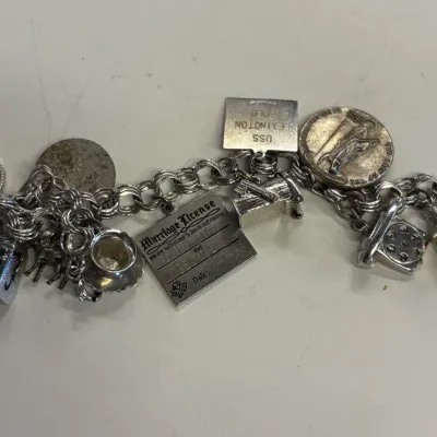 Vintage sterling silver charm bracelet featuring a variety of detailed charms, including a marriage license, rotary telephone, and...