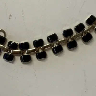 Vintage gold-tone link bracelet featuring rectangular black enamel or onyx-style inserts, secured with a toggle clasp.