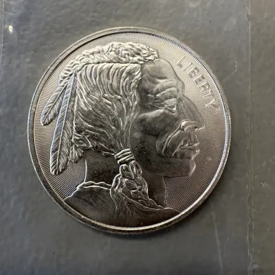 One ounce silver bullion round featuring a Buffalo Nickel-style Native American profile design, housed in a protective plastic sleeve.