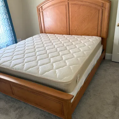 Traditional oak King-size bed frame featuring an arched panel headboard and matching footboard, complete with mattress and box spring.