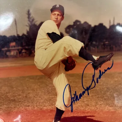 Autographed color photograph of baseball player Johnny Podres in a Brooklyn Dodgers uniform, signed in blue ink.