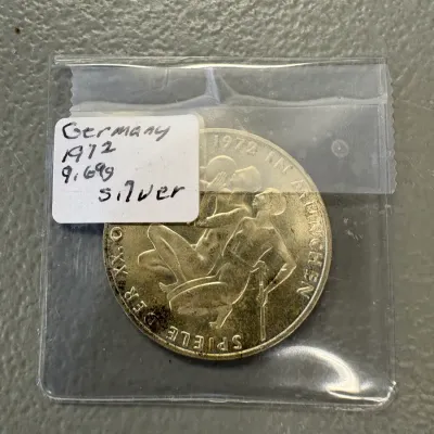 West German 1972 Munich Olympics silver commemorative coin, housed in a protective plastic sleeve with a handwritten label.