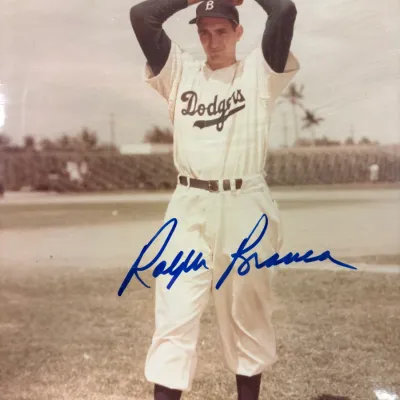 Autographed color photograph of Brooklyn Dodgers pitcher Ralph Branca in his windup, signed in blue ink across the center.