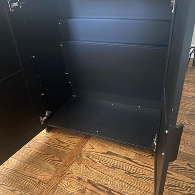 Sale Photo Thumbnail #532: Modern black double-door accent storage cabinet featuring shaker-style door panels and matching vertical handles. Open interior space without interior shelves currently installed (shelf pin holes present for adjustability). Minor superficial edge wear on 