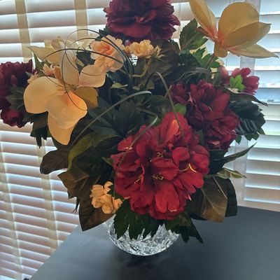 Sale Photo Thumbnail #539: Floral arrangement featuring faux burgundy and peach peonies, magnolias, and greenery set in a round cut crystal/glass rose bowl vase. Overall good condition with no visible chips or cracks to the glass.