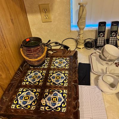 Carved wooden serving tray inset with six vibrant blue and yellow patterned ceramic tiles, displayed alongside kitchenware and electronics.