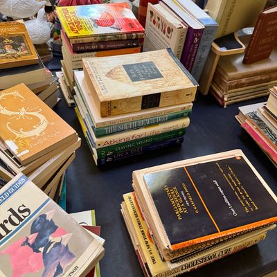 Assorted collection of vintage and modern books, including fiction, health guides, and reference materials, displayed on a table.