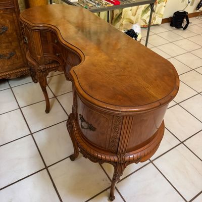 Vintage French Provincial style kidney-shaped wooden desk featuring ornate carved details, cabriole legs, and brass hardware.