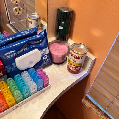 Assorted household items including a multi-day pill organizer, McKesson washcloths, a pink jar candle, a green pillar candle, and a...