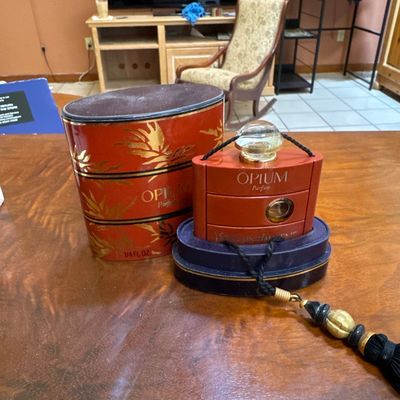 Vintage Yves Saint Laurent Opium Parfum 1/4 fl. oz. bottle with its original red and gold decorative box and black tassel accessory.