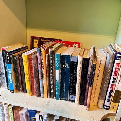 A collection of vintage and modern books, including titles by Deepak Chopra, Rod McKuen, and Shakespeare, arranged on two wooden shelves.