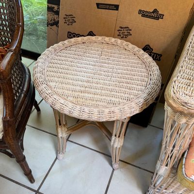 Vintage white wicker round side table with a woven top and wrapped legs, shown alongside matching wicker seating.