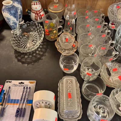 Assorted vintage glassware, including patterned mugs, tumblers, a butter dish, and decorative bowls, displayed alongside kitchen timers...