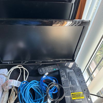 Sharp flat-screen television with remote, shown alongside a CyberPower 425VA uninterruptible power supply, power strips, and various cables.