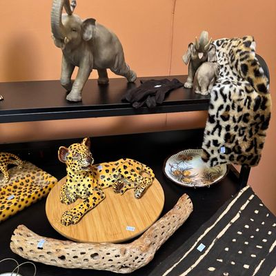 Assorted safari-themed decor items, including elephant figurines, a ceramic leopard on a wooden base, a piece of cholla wood, and leopard...