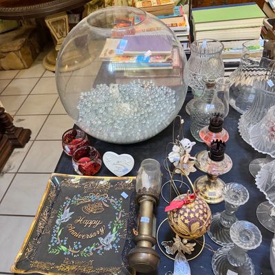 Assorted vintage tabletop decor including a large glass fishbowl filled with clear marbles, a black and gold "Happy...