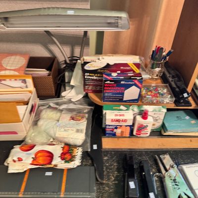 Assorted vintage office and desk supplies, including a gooseneck desk lamp, staplers, envelopes, and a paper trimmer.
