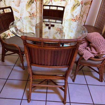 Vintage bamboo and rattan dining set featuring a round glass-top table and four matching chairs with upholstered seat cushions.