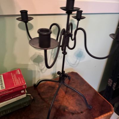 Wrought iron five-light candelabra with a rustic, hand-forged appearance, displayed on a wooden side table.