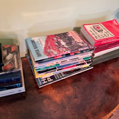 Assorted vintage books and magazines, including "Tropical Blossoms of the Caribbean" and a medical dictionary, stacked on a...