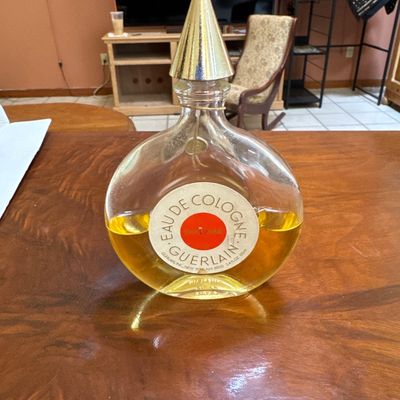 Vintage Guerlain Shalimar Eau de Cologne bottle, partially filled, featuring a round glass body and a gold-tone conical cap.