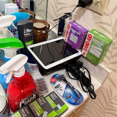Assorted personal care items, cleaning supplies, and electronics, including a Samsung tablet, Schick razor, Dove Men+Care soap, and...