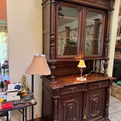Antique carved oak hutch featuring a glass-front upper cabinet with turned columns, two drawers, and a lower double-door cabinet with...