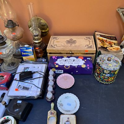 Assortment of vintage items including oil lamps, a wooden cigar box, a colorful floral tin, small decorative dishes, and various...