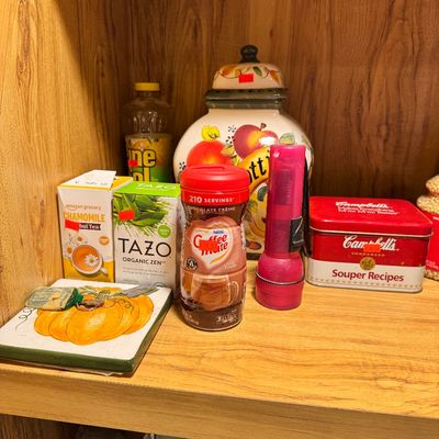 Assorted kitchen pantry items including Tazo tea, Coffee Mate creamer, a Campbell's recipe tin, and a ceramic cookie jar on a wooden...