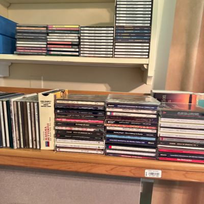Large collection of classical music CDs, including opera recordings like Madama Butterfly and Rigoletto, organized on wooden shelving.