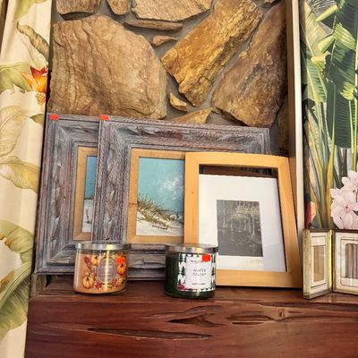 Assorted framed artwork, including a pair of coastal scenes in rustic gray wood frames and a black-and-white print in a light wood frame,...