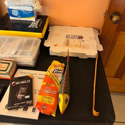 Assorted household items including a wooden fish decoration, a bamboo backscratcher, Odor-Eaters insoles, and an Apple iPod Touch screen...