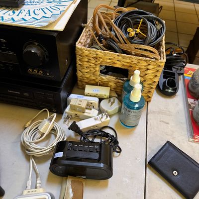 Assorted electronics and accessories, including a Sharp digital alarm clock, Belkin iPod dock, various power adapters, cables in a woven...
