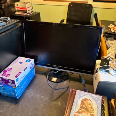 Dell flat-screen computer monitor on a desk, shown alongside boxes of nitrile gloves and religious books.
