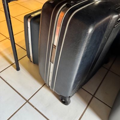 Vintage Samsonite hard-sided suitcases in dark grey or black, featuring aluminum trim and built-in wheels.