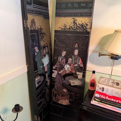Vintage Chinese black lacquer folding floor screen, featuring hand-painted and incised details depicting figures in a courtyard setting...